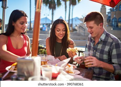 Group Of Friends Eating Meal Together At Outdoor Restaurant