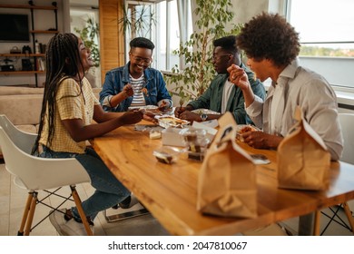 Group of friends eating a take-away food while sitting at the dining table