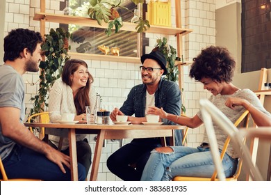 Group of friends enjoying in cafe together. Young people meeting in a cafe. Young men and women sitting at cafe table and smiling