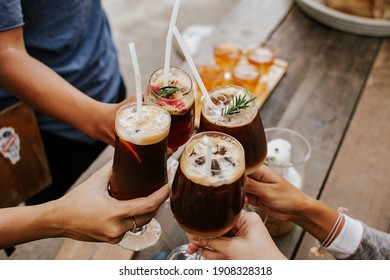 Group of friends enjoying coffe cocktail in wine glass. Creative new exotic cocktail drinks a combination of cold brew coffee with juice. 
				