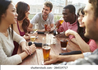 Group Of Friends Enjoying Drink At Outdoor Rooftop Bar