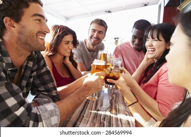 Group Of Friends Enjoying Drink At Outdoor Rooftop Bar