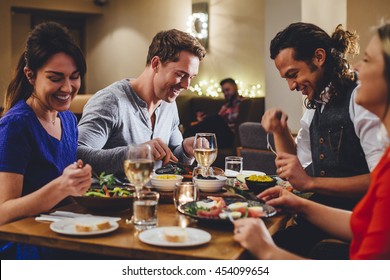 Group of friends enjoying an evening meal with wine at a restaurant.