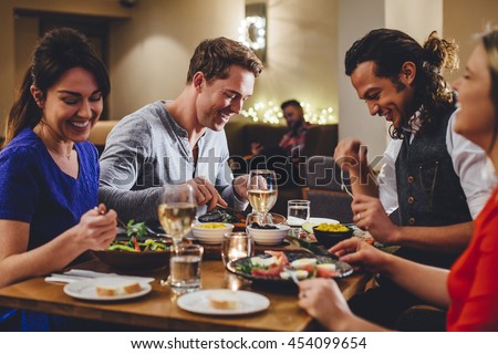 Group of friends enjoying an evening meal with wine at a restaurant.