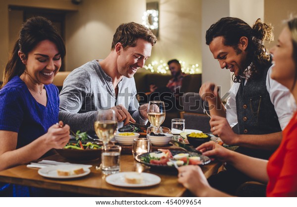 Group of friends enjoying an evening meal\
with wine at a\
restaurant.