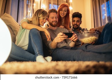 A Group Of Friends Enjoying A Late Night Movie On The Couch With Snacks.