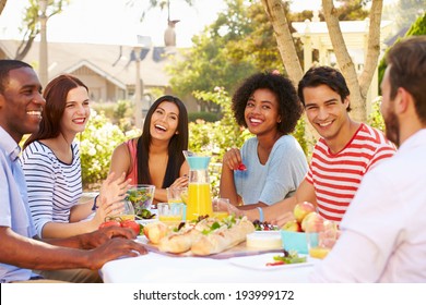 Group Of Friends Enjoying Meal At Outdoor Party In Back Yard