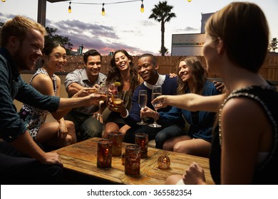 Group Of Friends Enjoying Night Out At Rooftop Bar