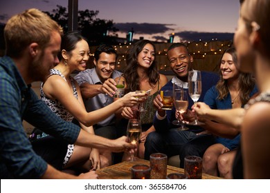 Group Of Friends Enjoying Night Out At Rooftop Bar