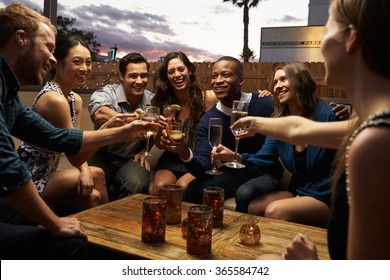 Group Of Friends Enjoying Night Out At Rooftop Bar