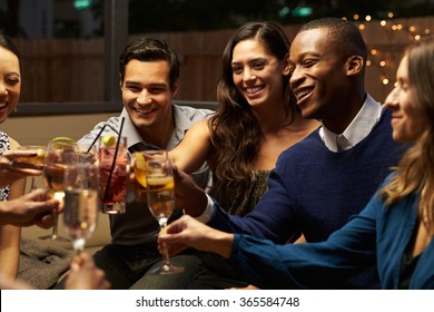 Group Of Friends Enjoying Night Out At Rooftop Bar