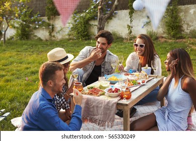 Group Of Friends Enjoying Outdoor Picnic In Garden - Powered by Shutterstock