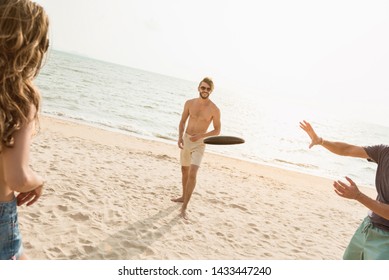 Group Of Friends Enjoying Playing Gliding Disc And Having Fun At The Beach On Summer Vacations