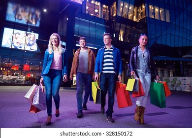 Group Of Friends Enjoying Shopping Trip Together Group Of Happy Young Frineds Enjoying Shopping Night And Walking On Steet On Night In With Mall In Background