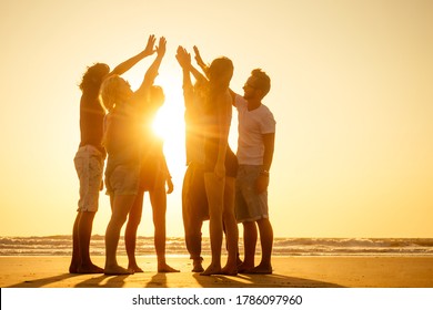 group of friends enjoying sunset in Goa India high five