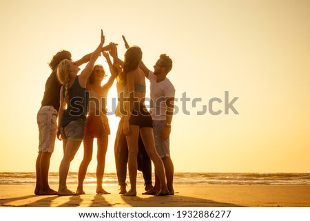 group of friends enjoying sunset in Goa India high five