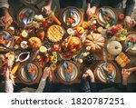 Group of friends or family members giving thanks to God at festive turkey dinner table together. Thanksgiving celebration traditional dinner concept