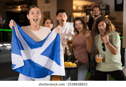 Group of friends fans watching match cheering with Scottish flag in bar - Powered by Shutterstock