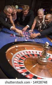 Group of friends gambling at roulette table in casino