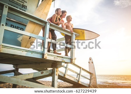 Group of friends going to surf at the beach - Young adults bonding at the beach