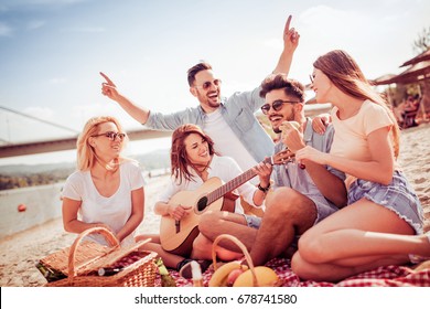 Group of friends with guitar having fun on the beach.Summer,holidays,vacation,music,people concept. - Powered by Shutterstock