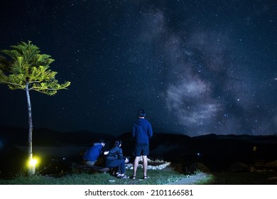 A Group Of Friends Hangs Out Under A Milky Way Galaxy At Night