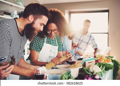 Group of friends happily passing time together and making dinner in light modern kitchen.  - Shutterstock ID 582618625