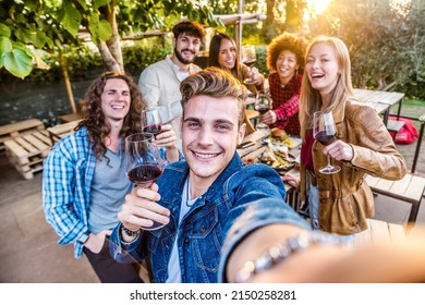 Group of friends having barbeque dinner party - Young people taking selfie drinking red wine together - Friendship concept with guys and girls dining outside - Bright filter - Powered by Shutterstock