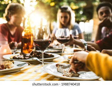 Group Of Friends Having Bbq Dinner Outdoor In Garden Restaurant - Multiracial Family Eating Food At Barbecue Backyard Home Party - Focus On Wine Glass