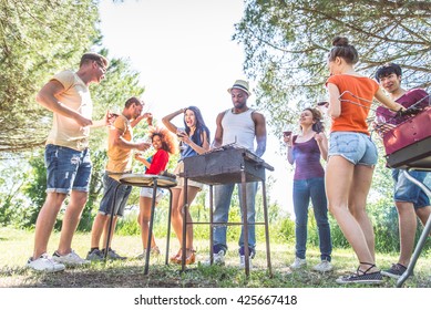 Group Of Friends Having Fun At Barbecue Party Outdoors - People Grilling, Dancing And Drinking Wine