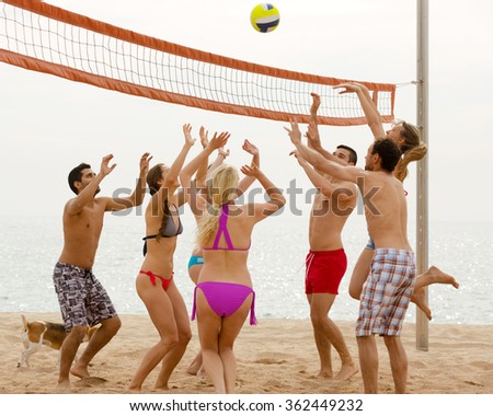 Group of friends having fun at beach and playing ball
