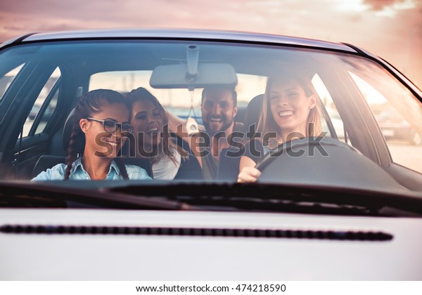 Group of friends\
having fun in the car.\
Sunset