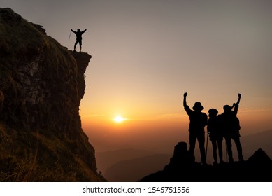 Group of friends having fun climbing. on sunset and mountains backdrop, Young happy tourist on top of a mountain.