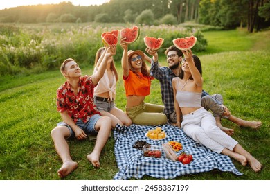 Group of friends having fun eating watermelon on the picnic outdoors. Foods, travel, nature and vacations concept - Powered by Shutterstock