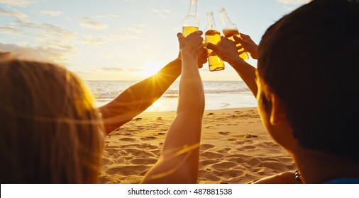 Group of friends having fun enjoying a beverage and relaxing on the beach at sunset - Powered by Shutterstock