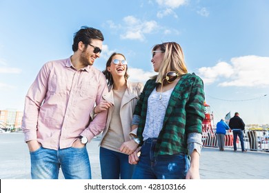 Group of friends having fun in Hamburg. They are two women, a Japanese and a German, and one middle eastern man, laughing and embracing. Friendship and lifestyle concepts.