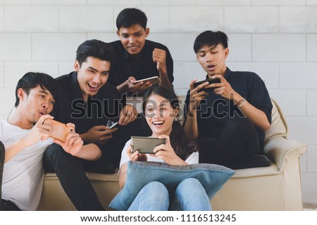 Group of friends having fun at living room and looking at smart phone, Asian teen watching football game in Mobilephone.