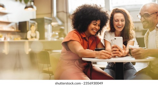 Group of friends having fun and making a video call, enjoying coffee and wi-fi at a local café. Happy young people hanging out together over a social lunch on the weekend. - Powered by Shutterstock