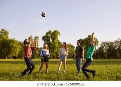 Group of friends having fun playing with a ball on a grass picnic in a summer park. - Powered by Shutterstock