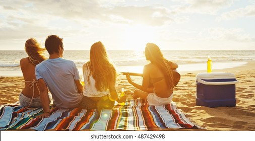 Group of friends having fun relaxing on the beach at sunset - Powered by Shutterstock