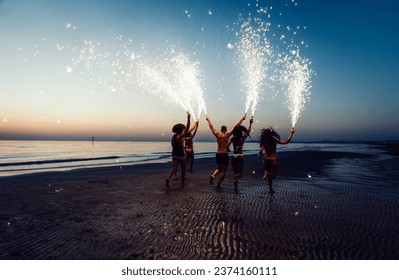 Group of friends having fun running on the beach with sparklers - Powered by Shutterstock