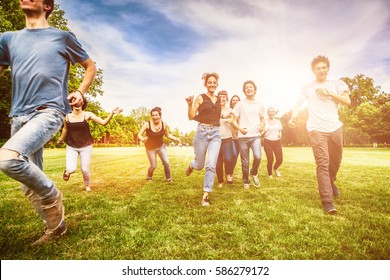Group of friends having fun and running on green meadow - Shutterstock ID 586279172
