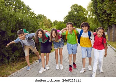 Group of friends having fun together. Six happy children playing outside after school. Several elementary students in casual clothes standing on park path, hugging, smiling and looking at camera - Powered by Shutterstock