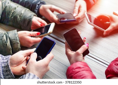 Group of friends having fun together with smartphones - Closeup of hands social networking with mobile cellphones - Technology and phone addiction concept - Soft focus on the left bottom hand
