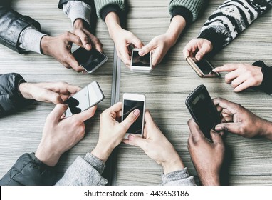 Group of friends having fun together with smartphones - Closeup of hands social networking with mobile phones - Technology and phone addiction concept - Main focus on bottom hands - Vintage filter - Powered by Shutterstock