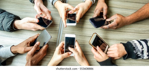 Group of friends having fun together with smartphones - Closeup of hands social networking with mobile cellphones - Wifi connected people in bar Technology and phone addiction concept - Warm filter