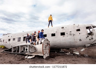 group of friends having fun walking over the wreck of a plane in Iceland