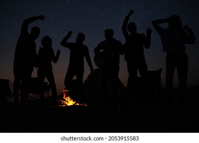 Group of friends having party near bonfire at night. Camping season