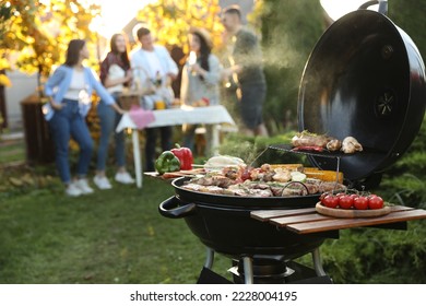 Group of friends having party outdoors. Focus on barbecue grill with food. Space for text - Powered by Shutterstock