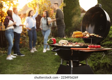 Group of friends having party outdoors. Focus on barbecue grill with food. Space for text - Shutterstock ID 2234956269